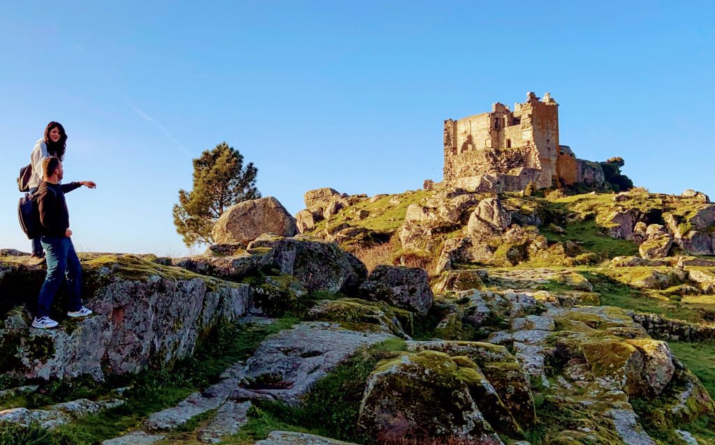 Dos personas paradas encima de rocas al lado del castillo de Trevejo