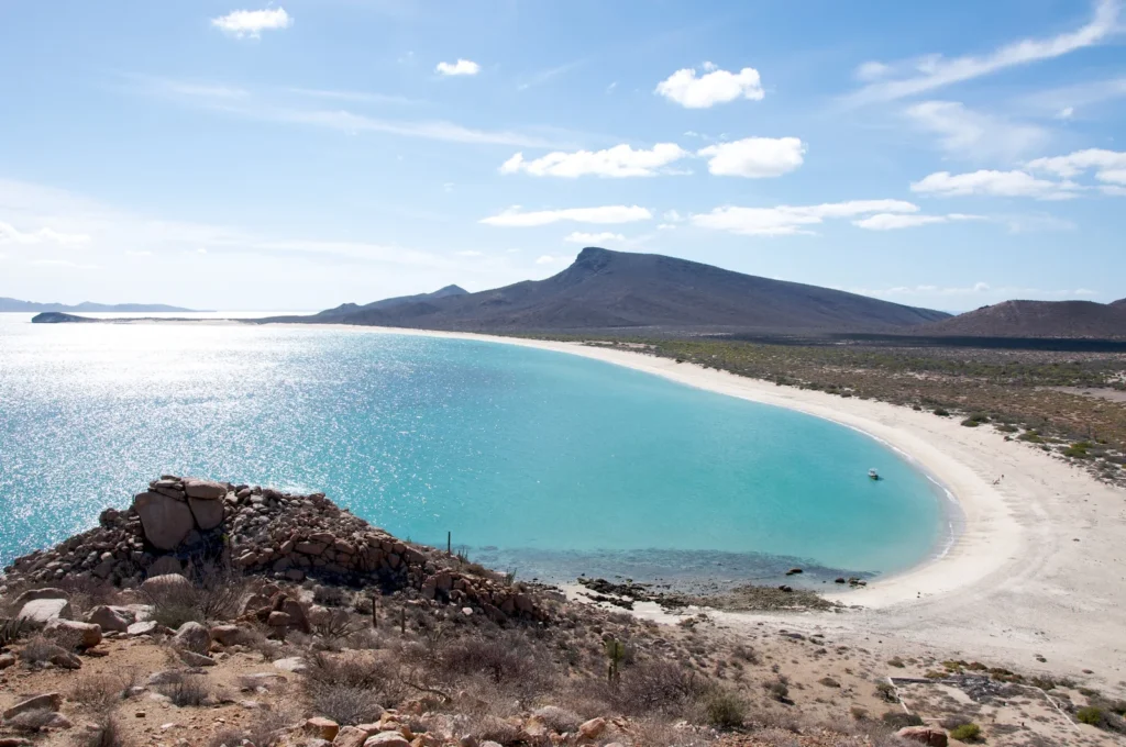Playa de Isla Espíritu Santo con arena clara y montes áridos al fondo