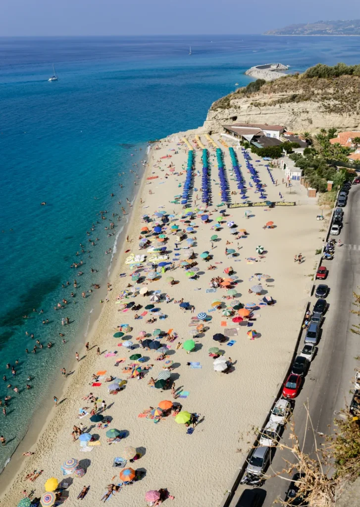 Playa de Tropea con arena clara y acantilado del centro histórico