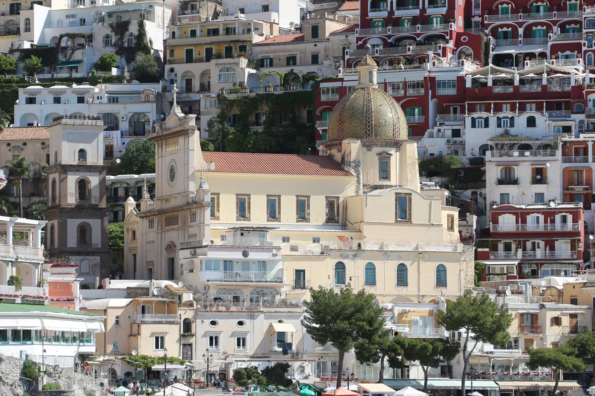 Cúpula de azulejos y campanario de Santa Maria Assunta entre las casas de Positano