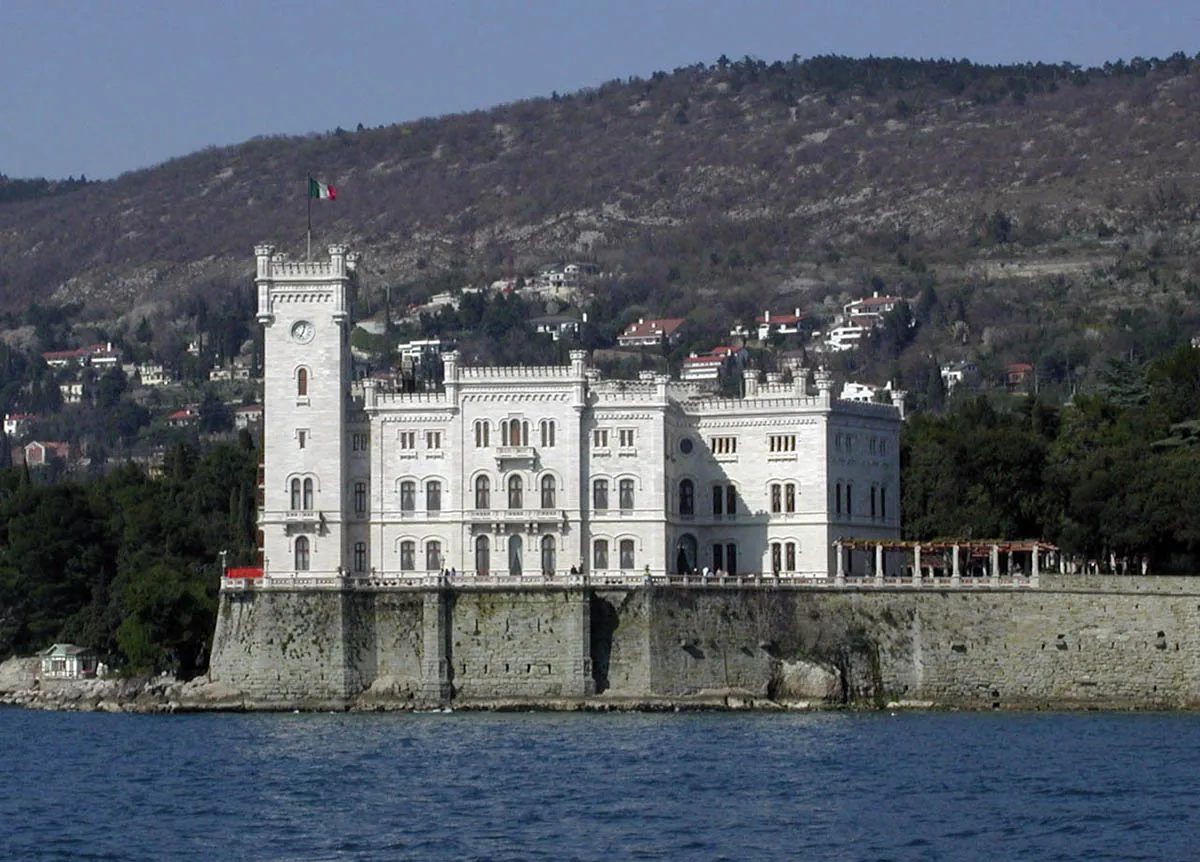 Castillo blanco de Miramare junto al mar, con la ladera al fondo