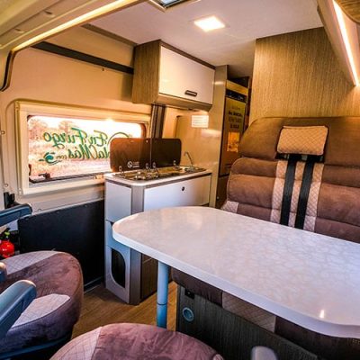 El interior de un rv con una mesa y sillas.