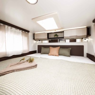 Un dormitorio en una autocaravana con una cama y una mesita de noche.