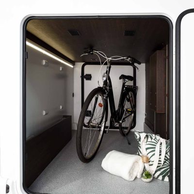 Una autocaravana blanca con una bicicleta en la puerta.