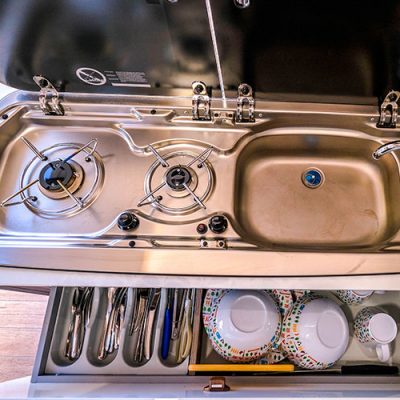 Una cocina con fregadero, estufa y utensilios.