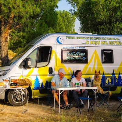 Un grupo de personas sentadas en una mesa frente a una autocaravana.